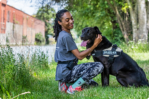 Animal Care Assistant walking a dog in a shady spot alongside the canal
