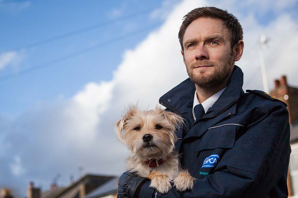 An RSPCA inspector holding a dog in his arms.
