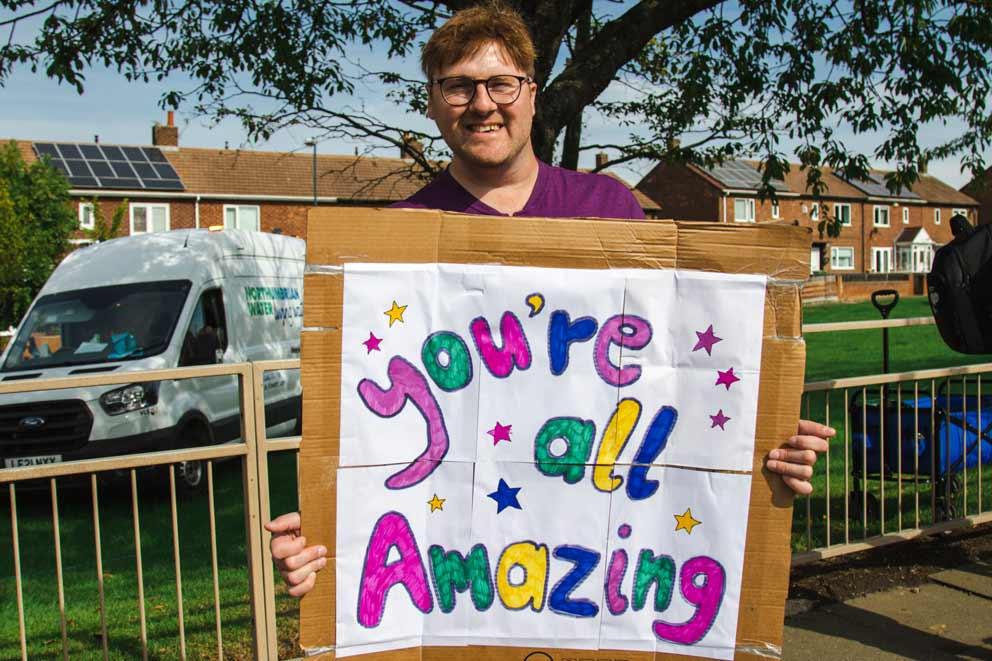 A main holding a banner to support runners.