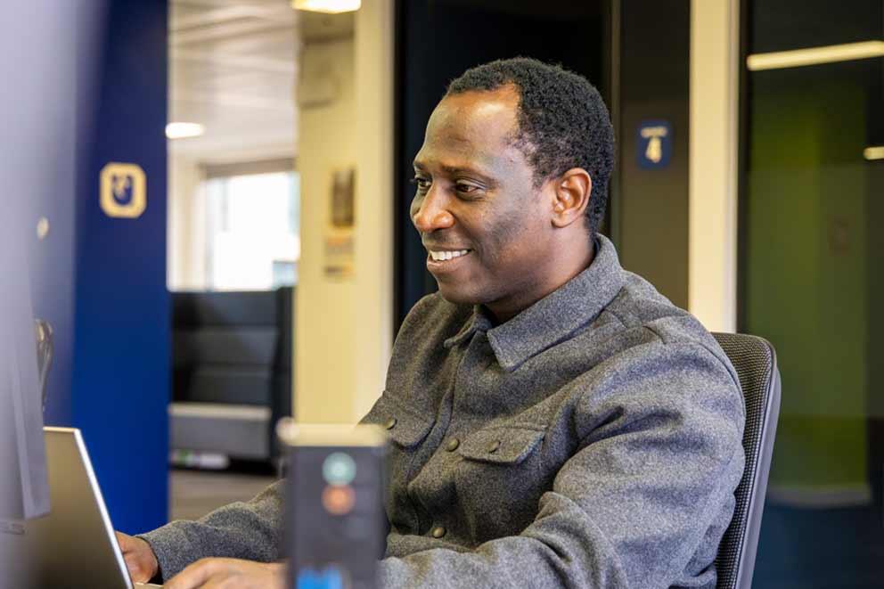 A man working with his laptop on a desk looking at the screen..