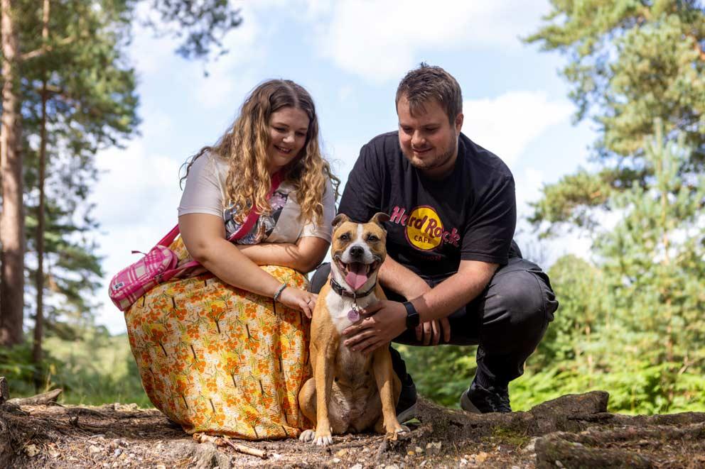 Happy looking dog with their new owner outside in the woods.