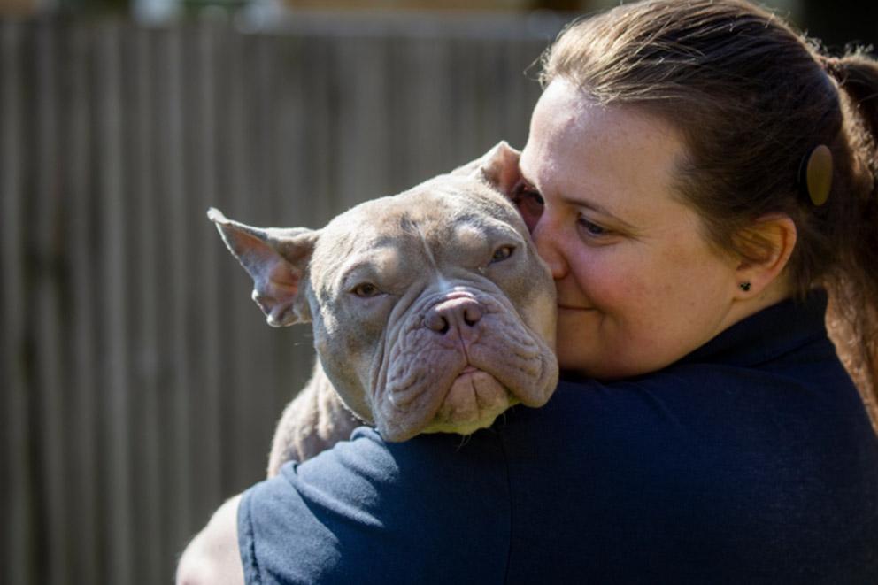 woman holding her french bulldog and smiling