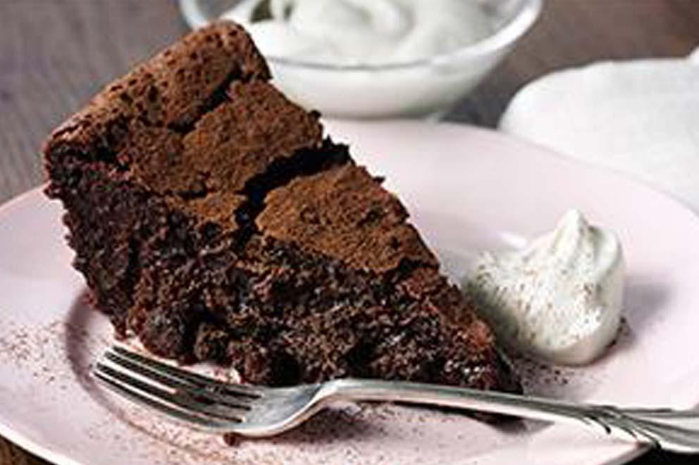 A slice of chocolate cake with a dollop of cream on a plate with a cake fork.