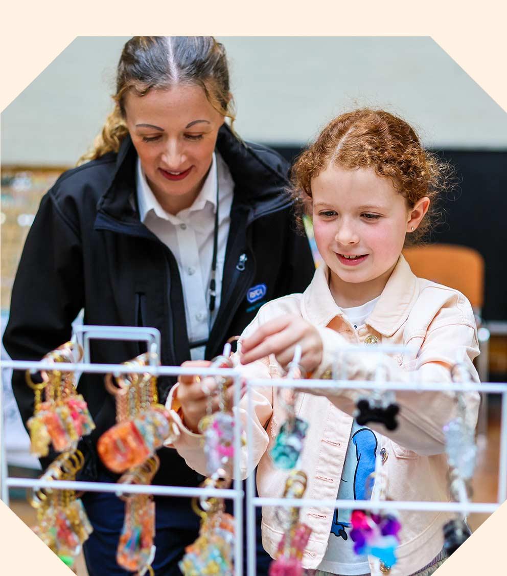 A woman and a child looking at keyrings on a stand