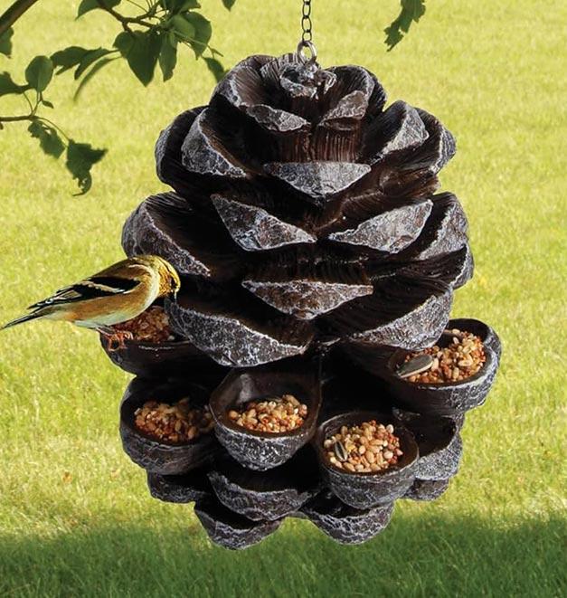 Birds feeding from a bird food hanger shaped like a pine cone.