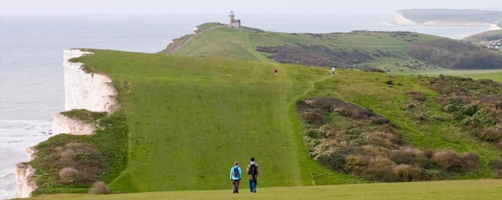 Two trekkers walking the South Downs way towards Beachy Head in Sussex.