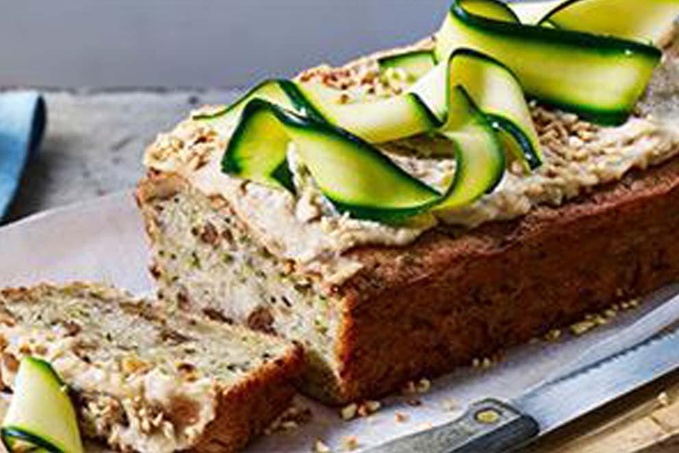 A close-up of a vegan courgette loaf with sliced ribboned courgette used as decoration.